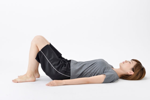 仰向けで膝を立て、静かに息を吐いているリラックスした姿