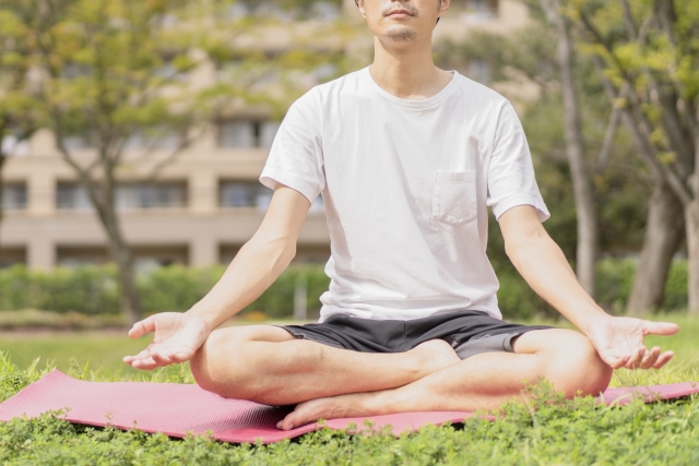 屋外で座り、両手を広げて呼吸を整えている男性
