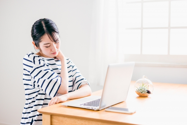 デスクで頬杖をついて、疲れた表情の女性