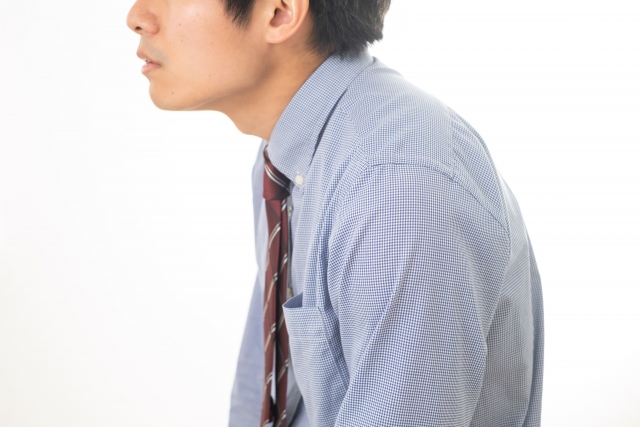 前かがみになっているビジネスパーソンを横から見たところ
