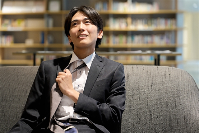 ソファに座って、ネクタイをゆるめて一息ついているスーツ姿の男性