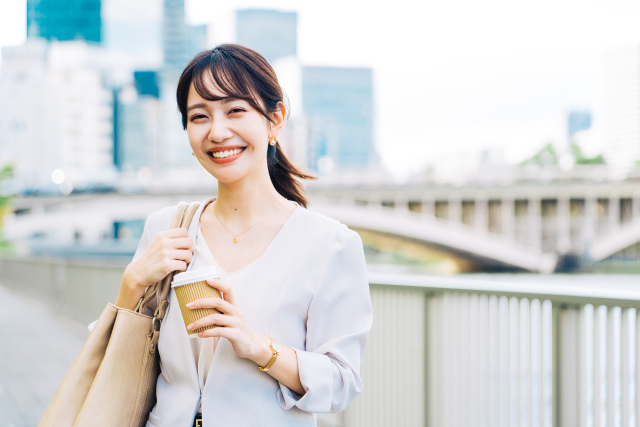 コーヒーを片手に出勤する笑顔の女性