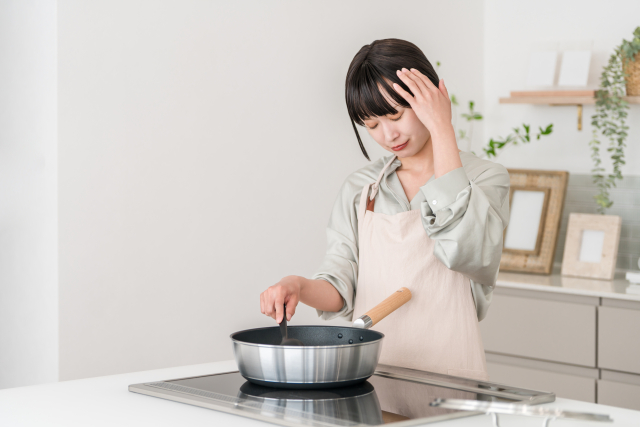 キッチンで、食事の準備に頭を抱えている女性