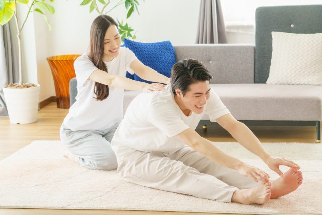 室内で男女が並んで、無理のない範囲でストレッチをしている様子